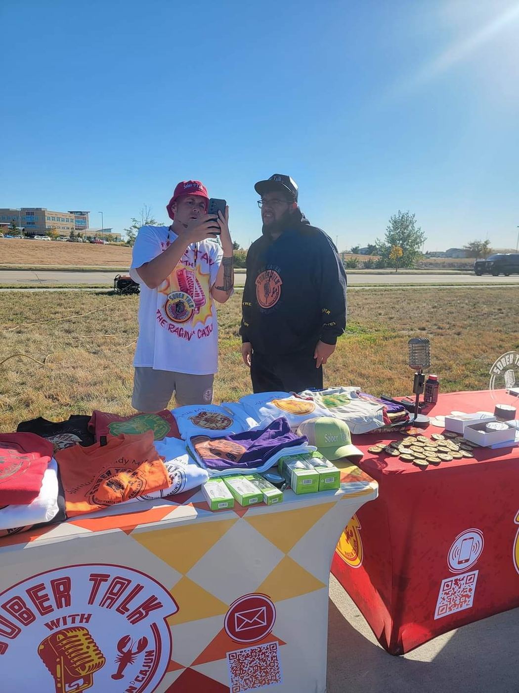 Brandon taking a photo beside the outdoor SoberTalk merch tables