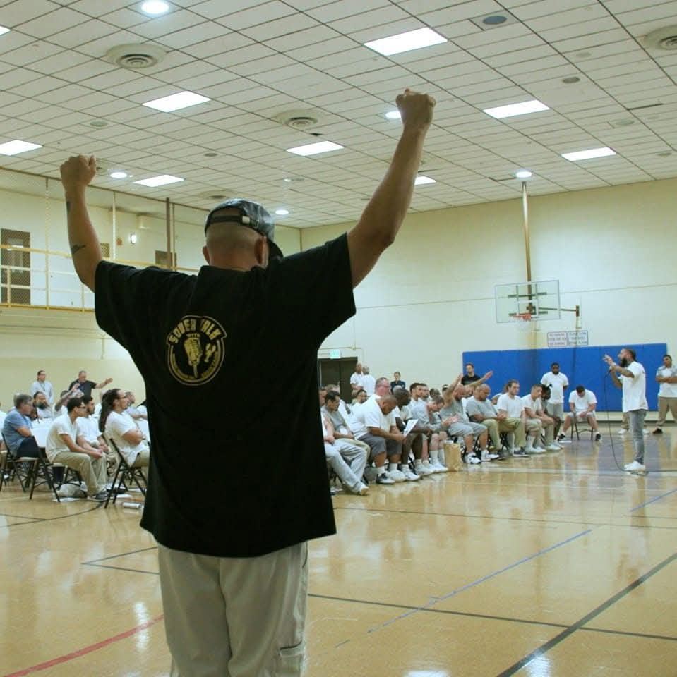 Brandon with both arms raised in front of a crowd in a gym