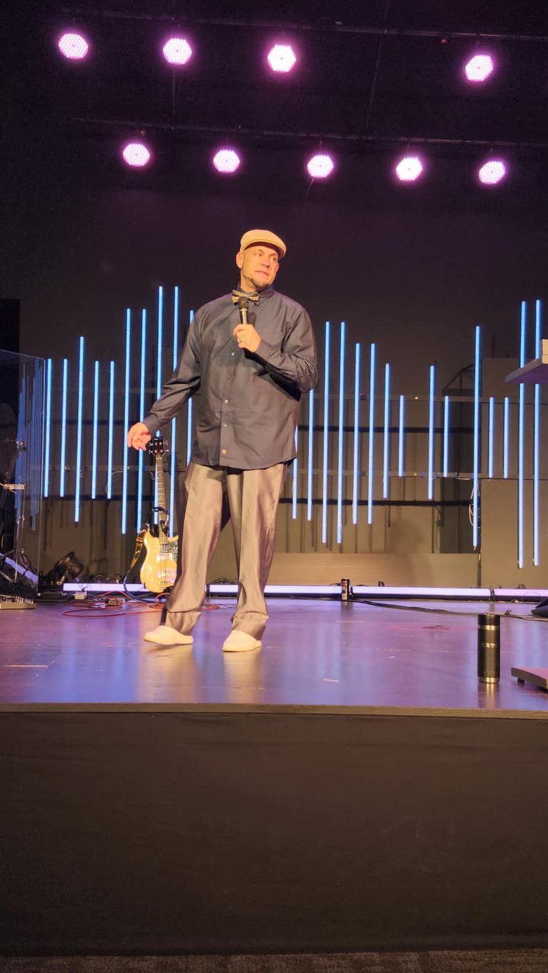 Brandon speaking on a church stage under purple lights
